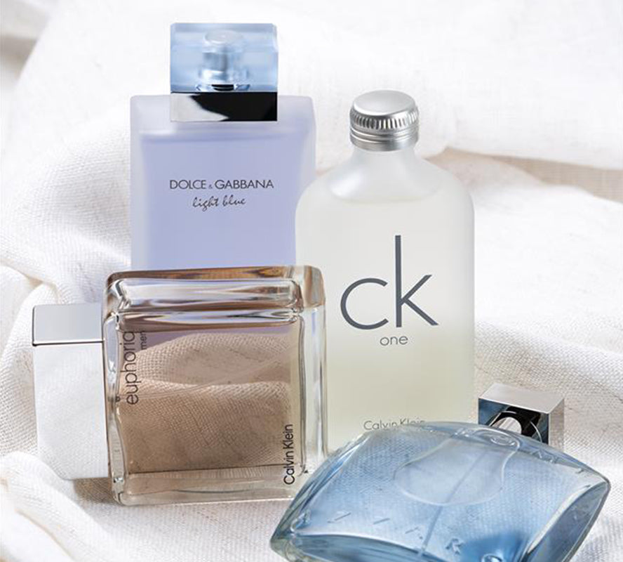 Assorted designer perfume bottles arranged on soft white fabric.
