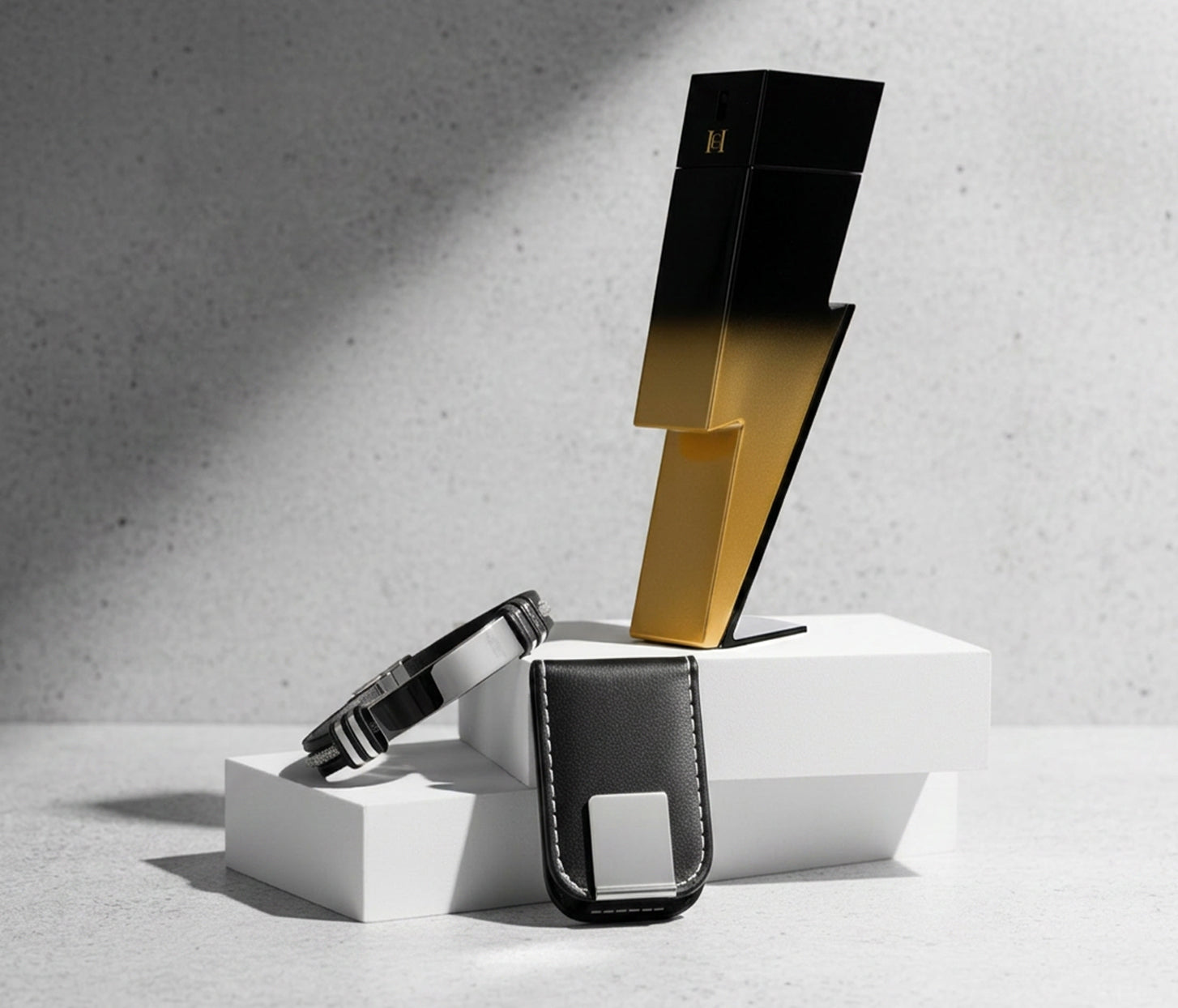Carolina Herrera Bad Boy fragrance bottle styled on white display blocks with luxury men’s accessories and dramatic shadows.